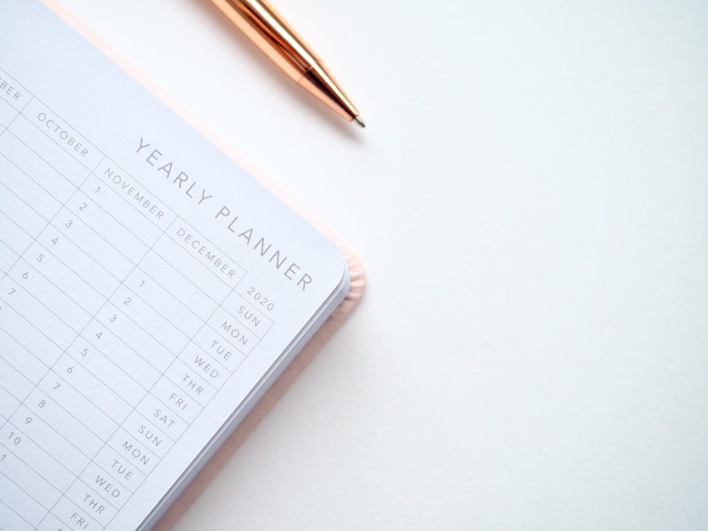 yearly planner and gold pen on white desk 