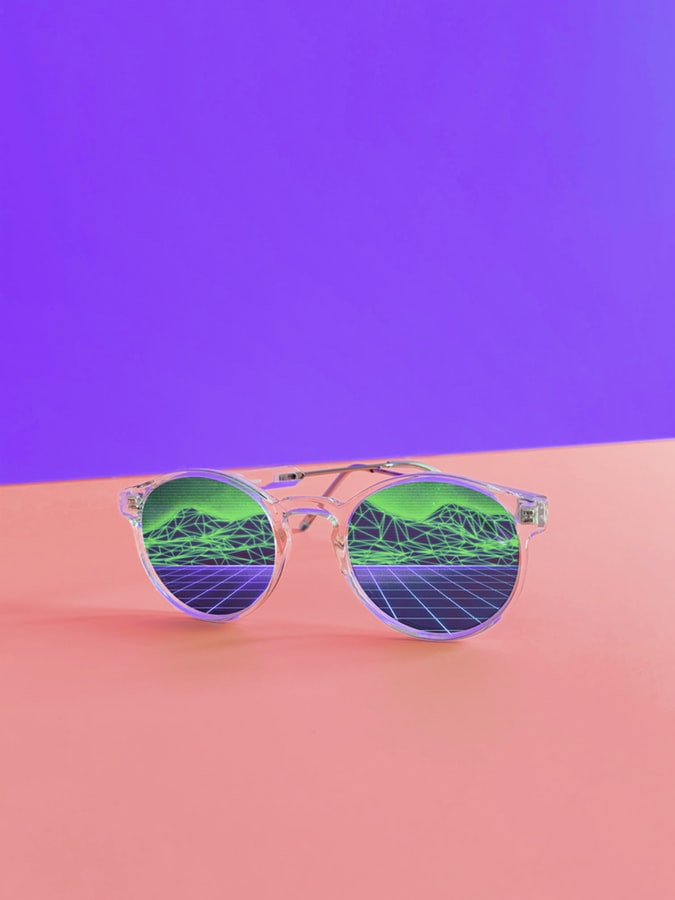 sunglasses with mountains reflected on purple and pink background