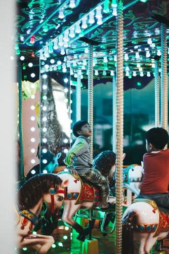 small asian boy on blue lighted carousel 