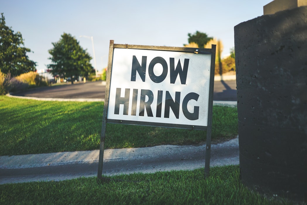 now hiring sign on green grass