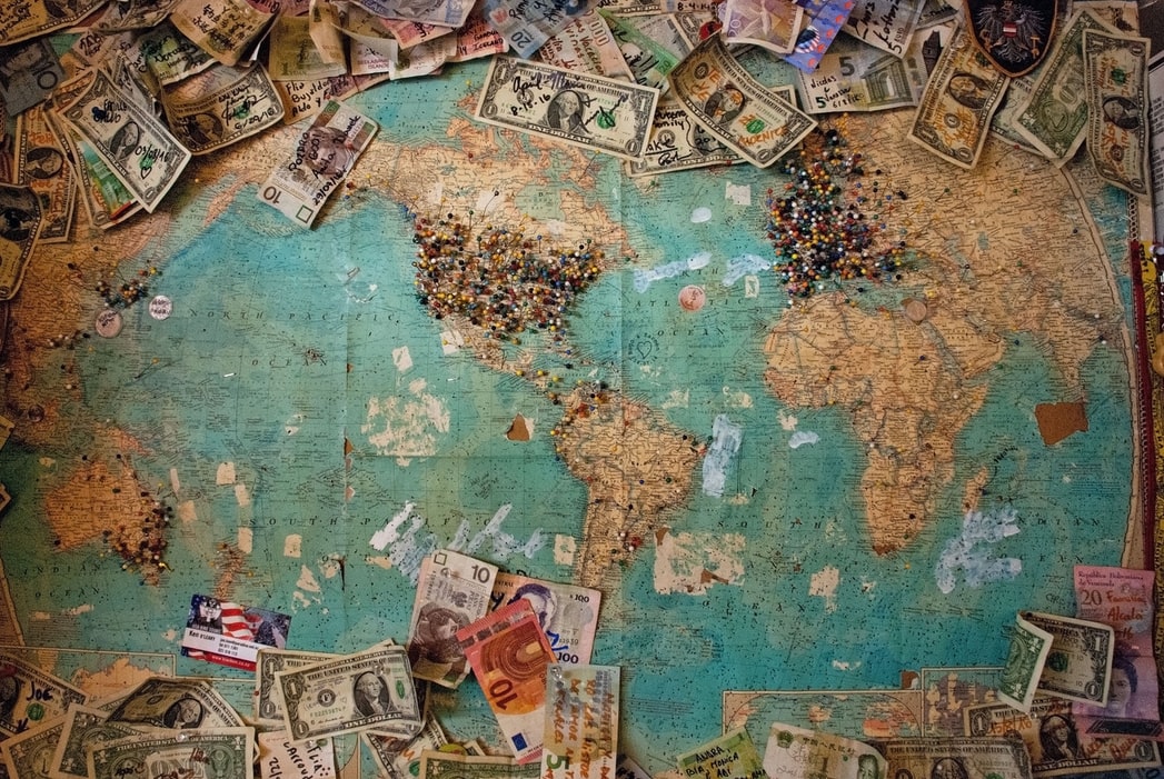 world map with different world currencies around it 