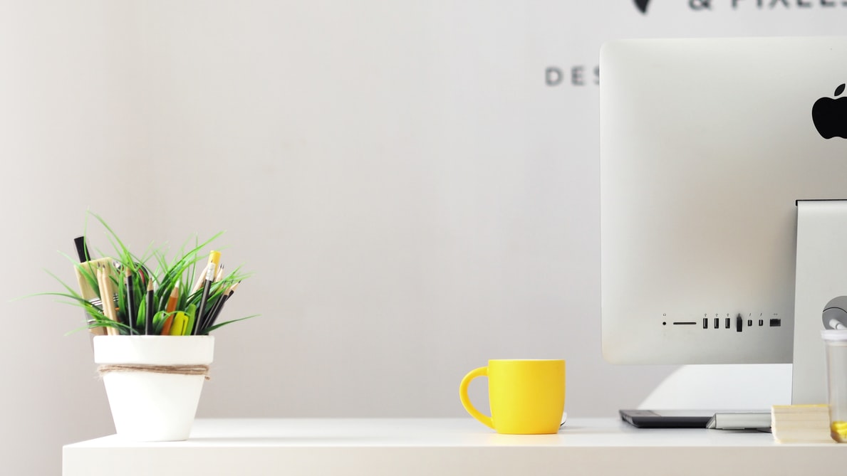 office desk set up with computer, yellow mug, and pen holder