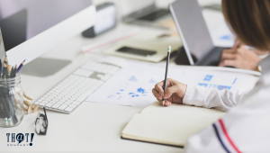 User Interface | A Girl At An Office Desk Writing In A Notebook 