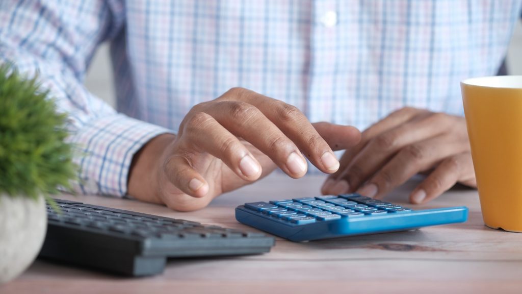 Primer plano de la mano del hombre usando la calculadora.