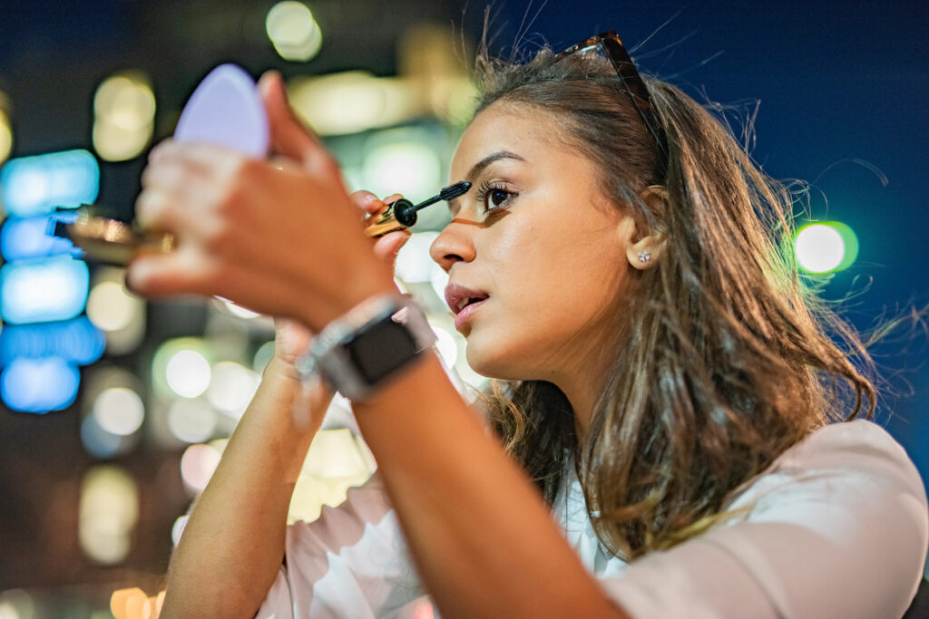 夜にマスカラを塗る若い女性のポートレート