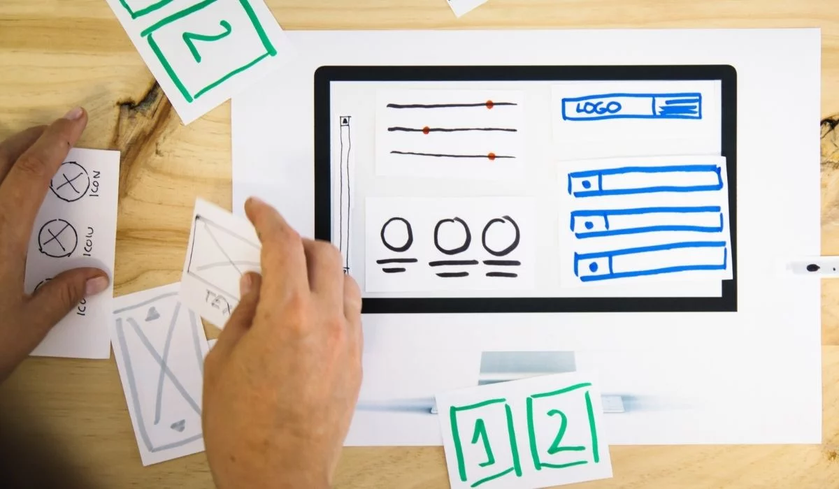 Tangan laki-laki memindahkan elemen situs web pada IA ​​yang digambar tangan atau tata letak situs web wireframe