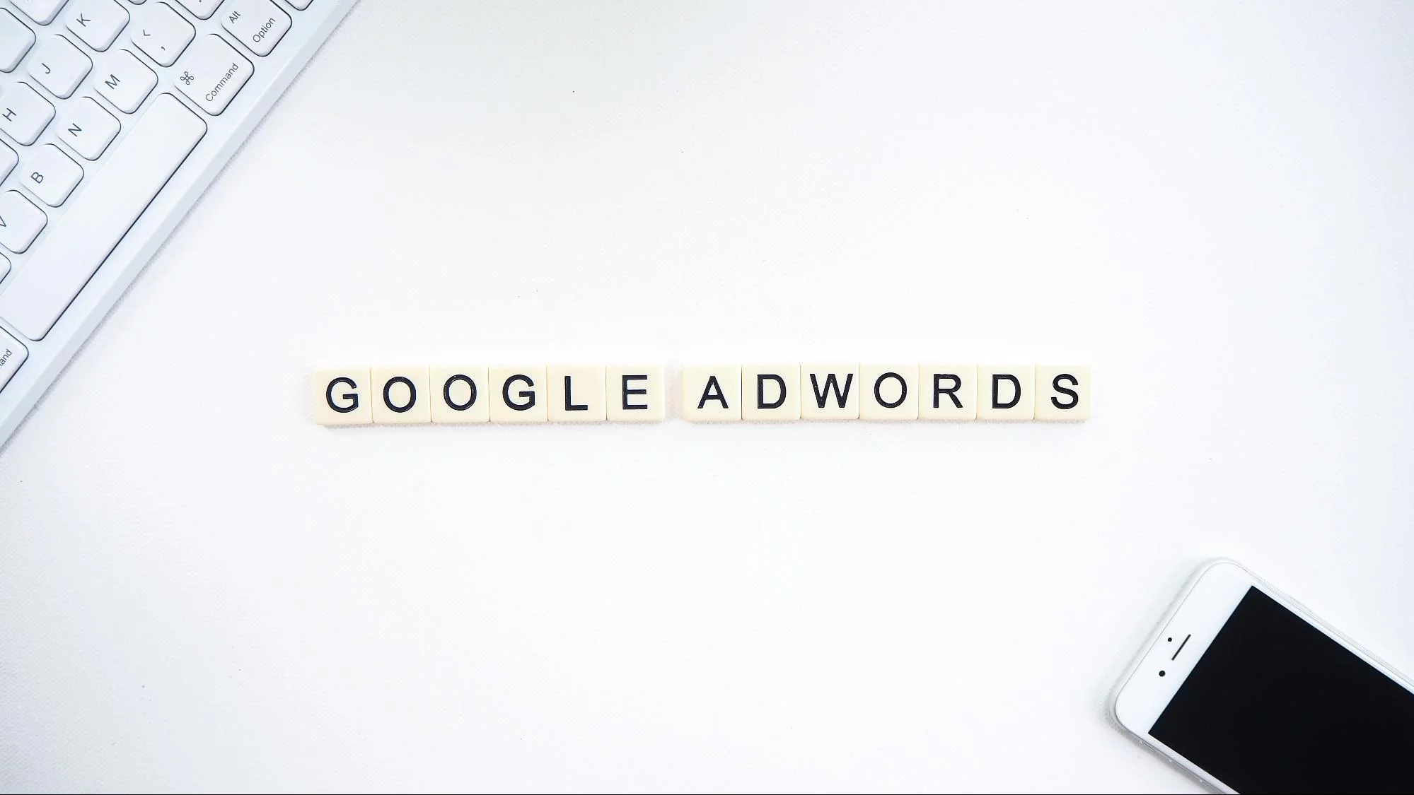 sol üst köşede bir anahtar kelimenin, sol altta bir akıllı telefonun ve ortada Google Adwords kelimelerinin gösterildiği beyaz arka plan