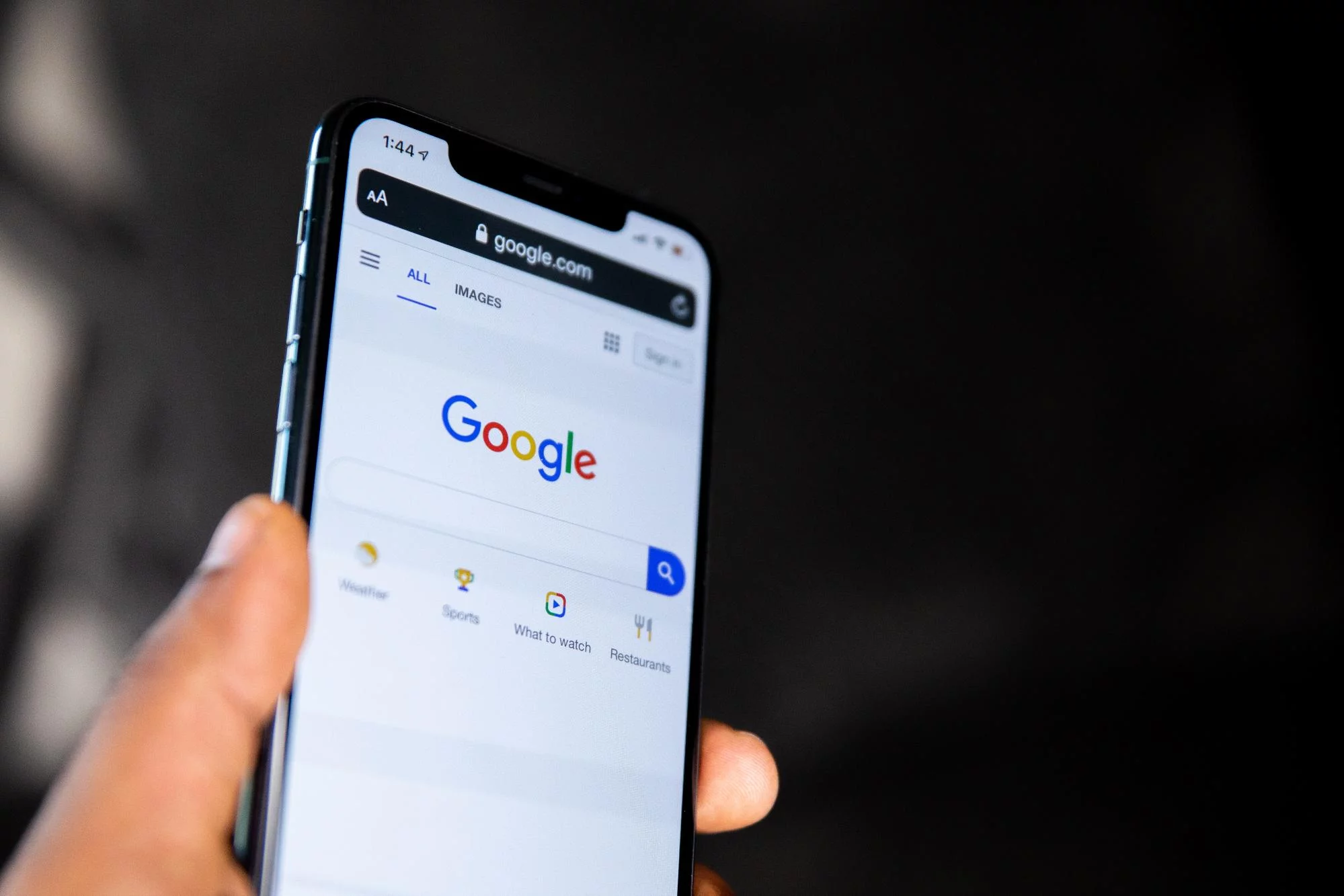 La main gauche d'un homme tenant un smartphone avec la recherche Google relevée