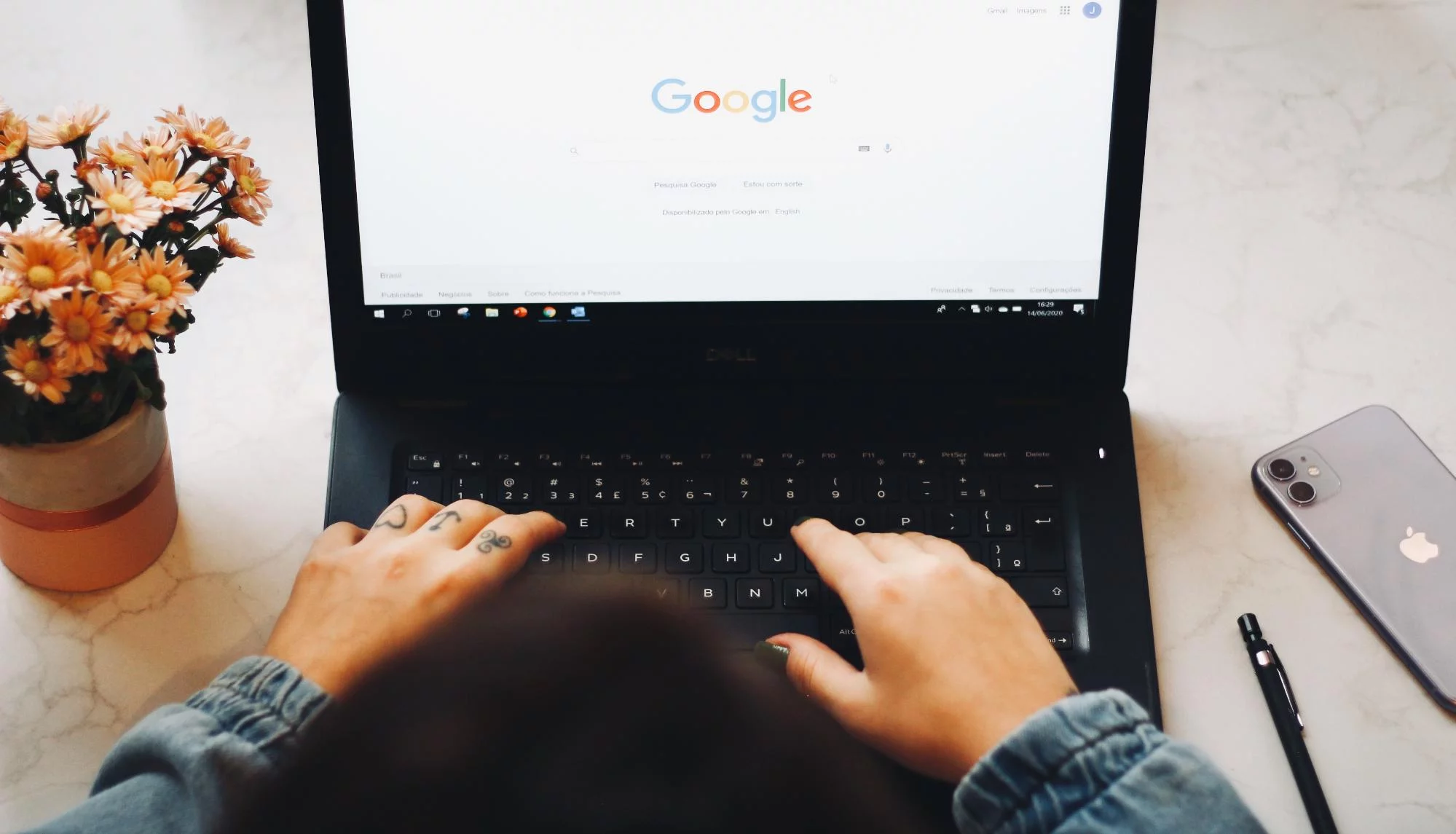 Um laptop com as mãos no teclado e a Pesquisa Google na tela