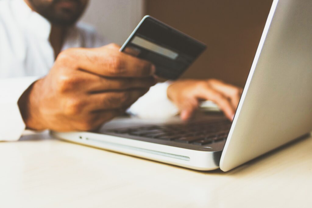 Homem no laptop com um cartão de crédito na mão