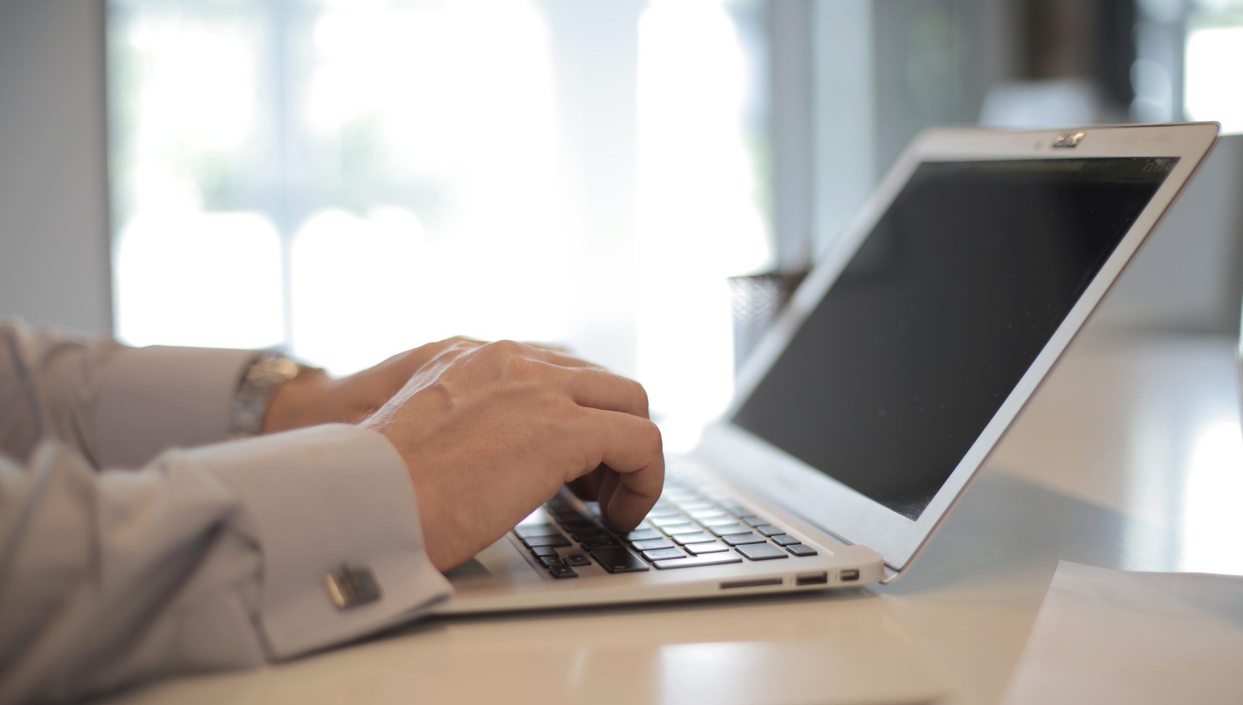 Un hombre que usa una computadora portátil en una mesa blanca