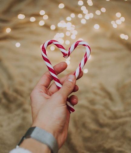 mãos segurando bastões de doces em corações no natal