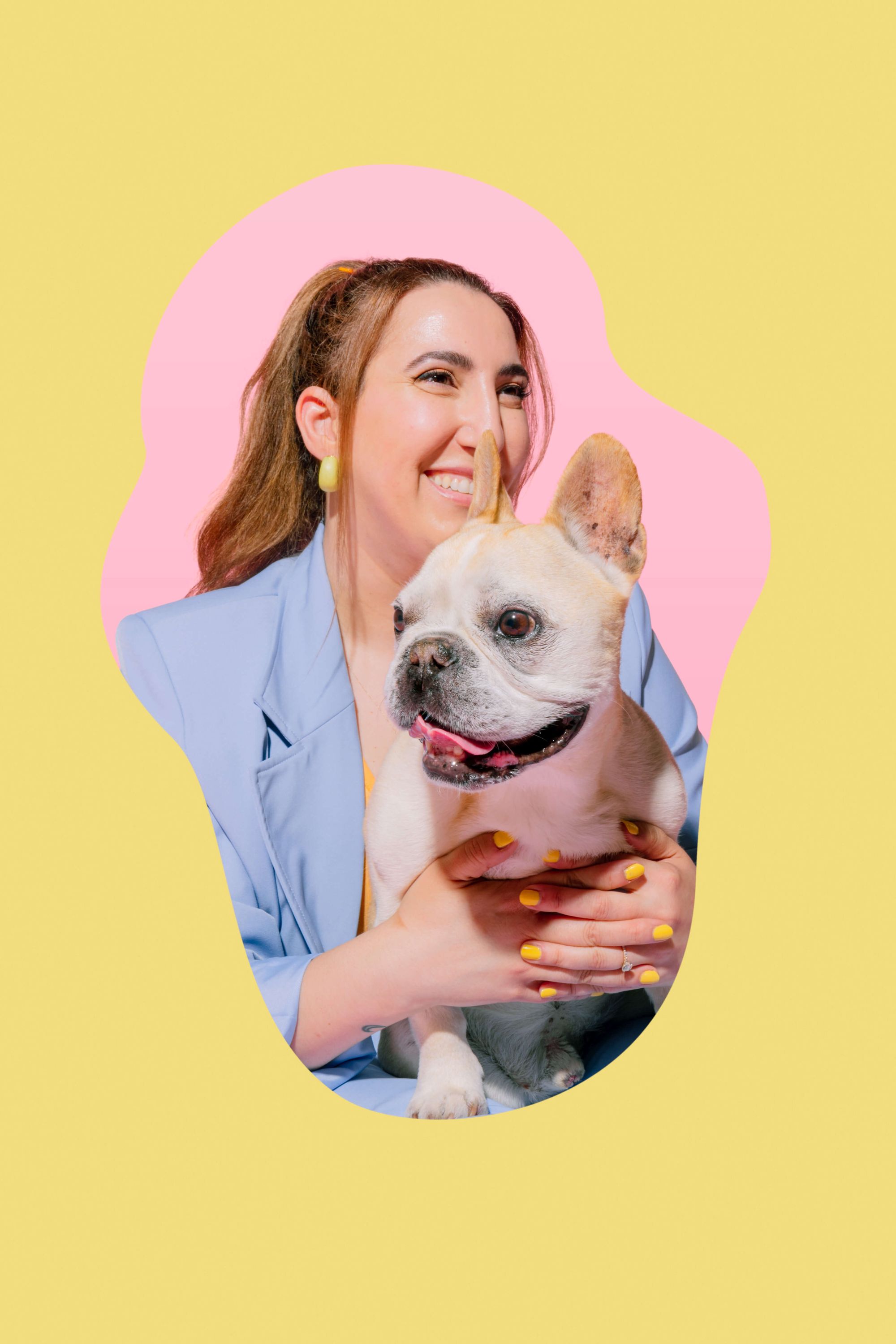 Una imagen de la fundadora, Leda, sonriendo y mirando a lo lejos mientras sostiene a su Bulldog francés, Handsome. Guapo tiene pelaje blanco y está sacando la lengua.