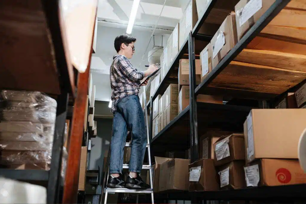 Employé d'entrepôt vérifiant l'emplacement du bac sur l'échelle