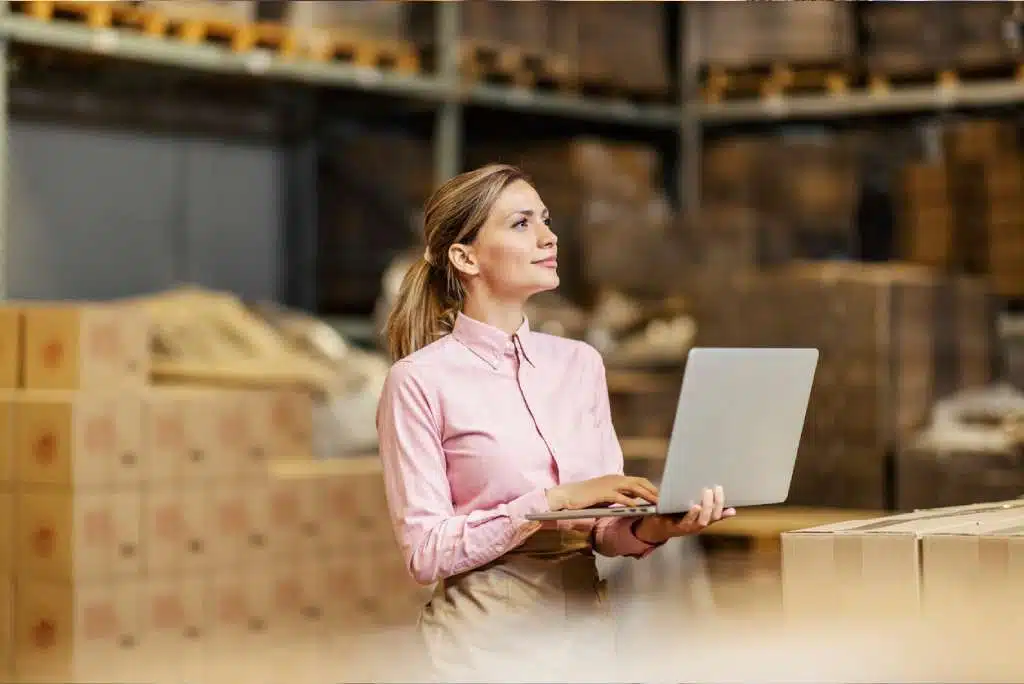 Femme utilisant un logiciel de gestion d'entrepôt sur un ordinateur portable