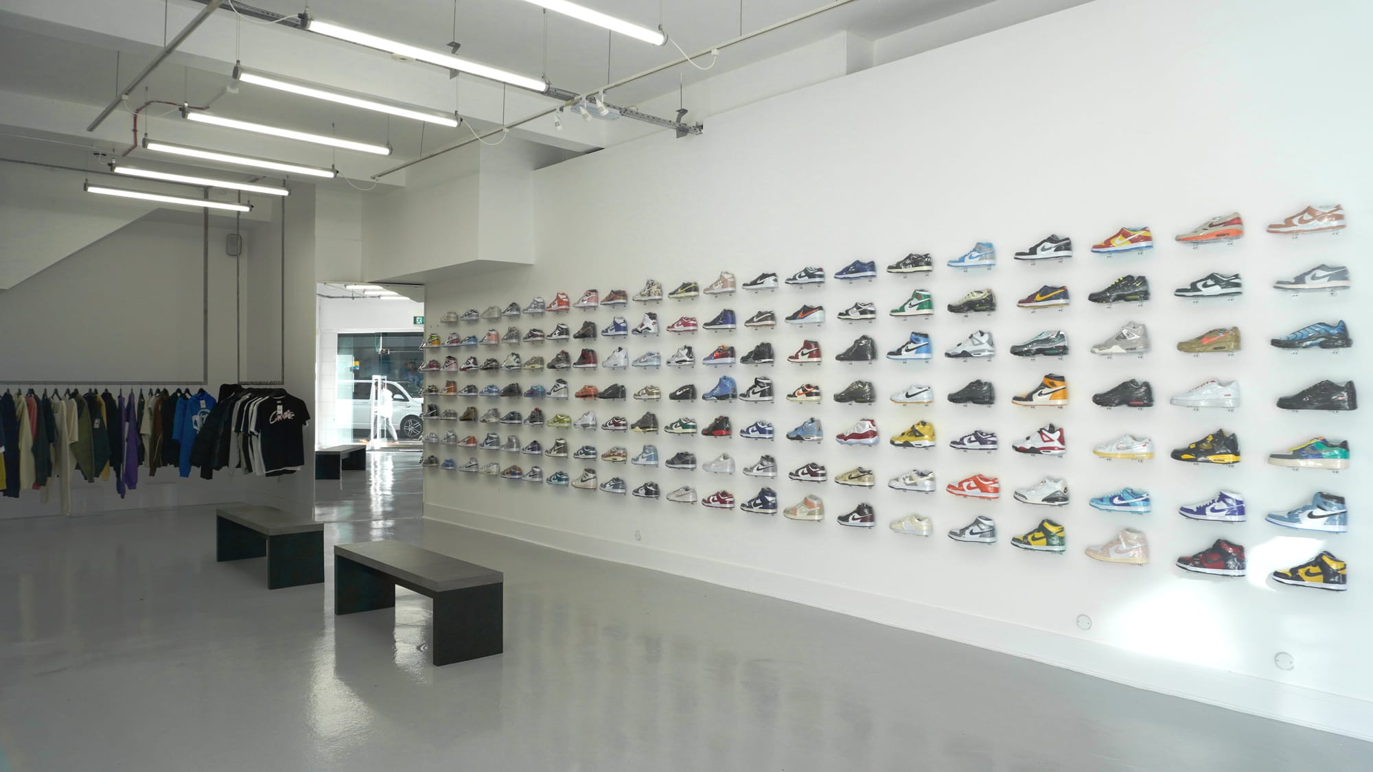 Ein Bild des Side Kicks Stores. Es zeigt eine weiße Wand voller Dutzender ausgestellter Turnschuhe.