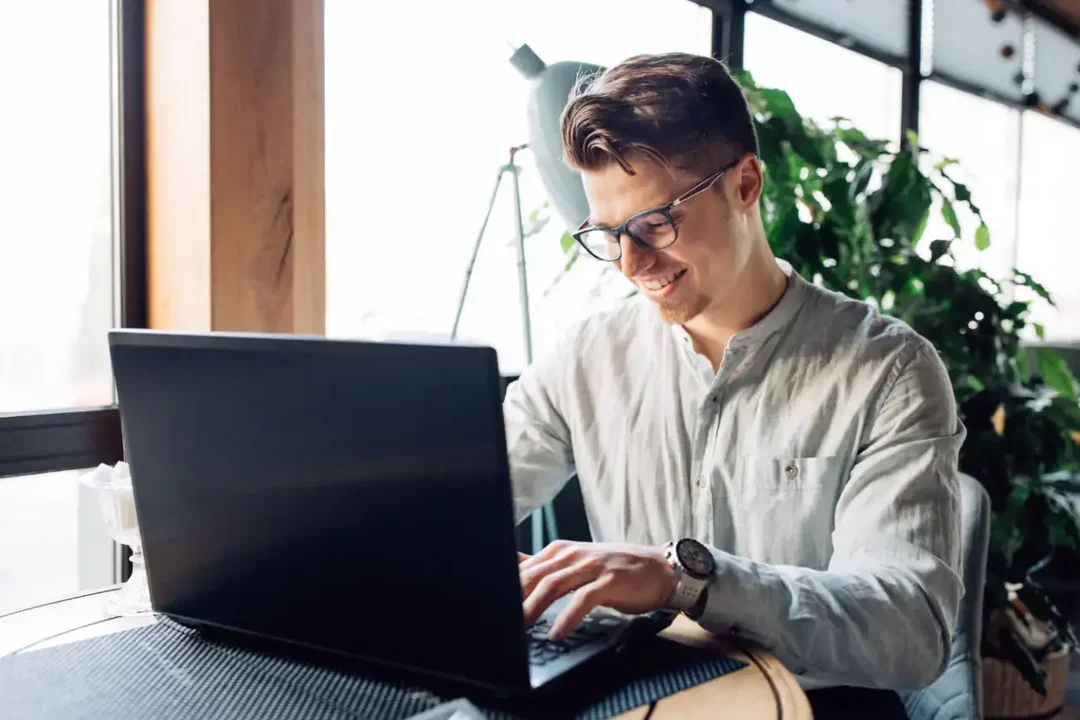 atraente-empresário-óculos-trabalhando-laptop-digitando-passando-tempo-café