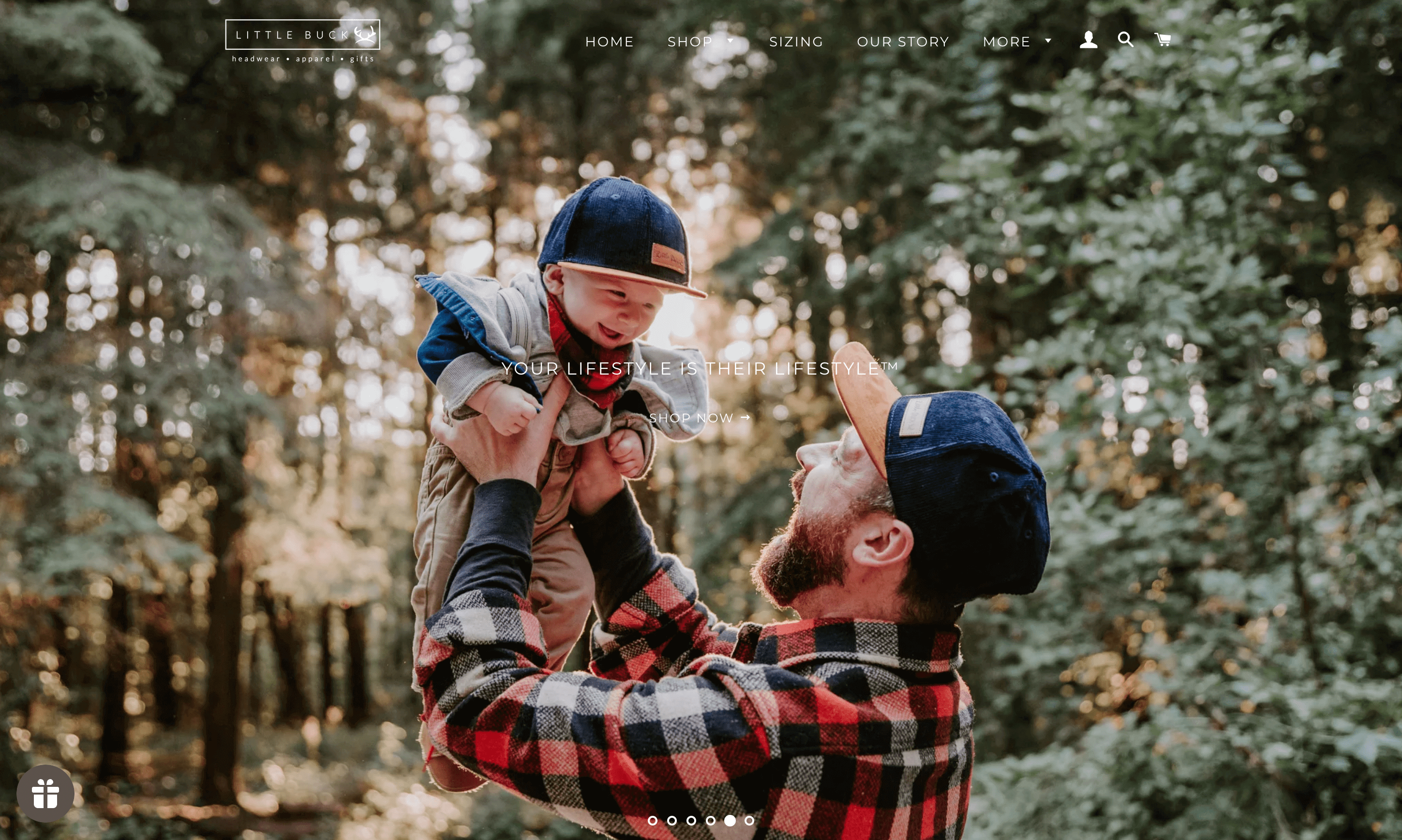 Little Buck 主页的屏幕截图显示，一位爸爸抱着他的孩子，戴着配套的后扣海军蓝色 Little Buck 帽子。