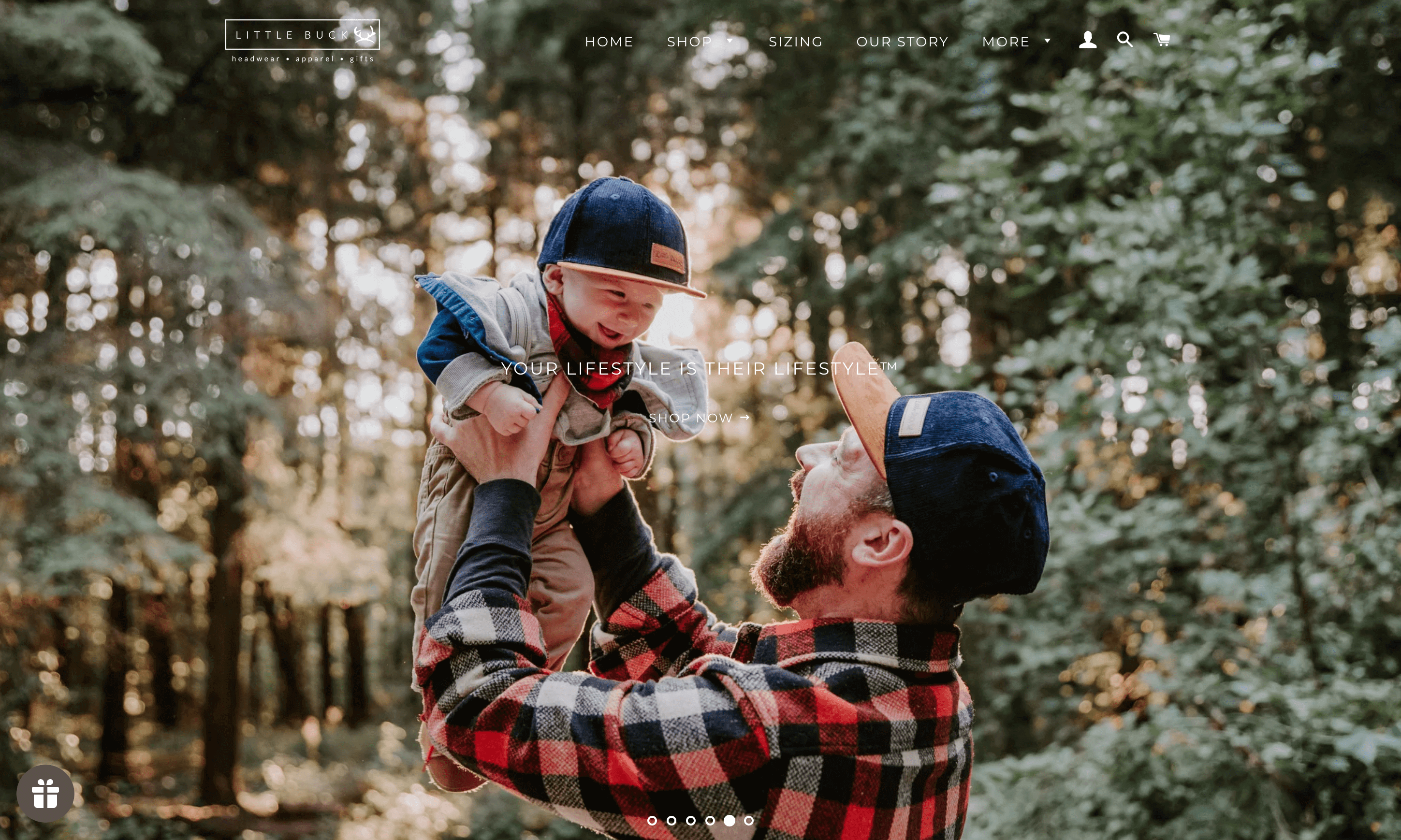 Ein Screenshot der Homepage von Little Buck zeigt einen Vater, der sein Baby in passenden marineblauen Snapback-Mützen von Little Buck hält.