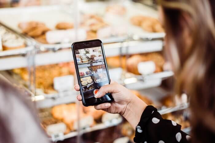 Une jeune femme prend une vidéo de délicieuses pâtisseries dans un café.