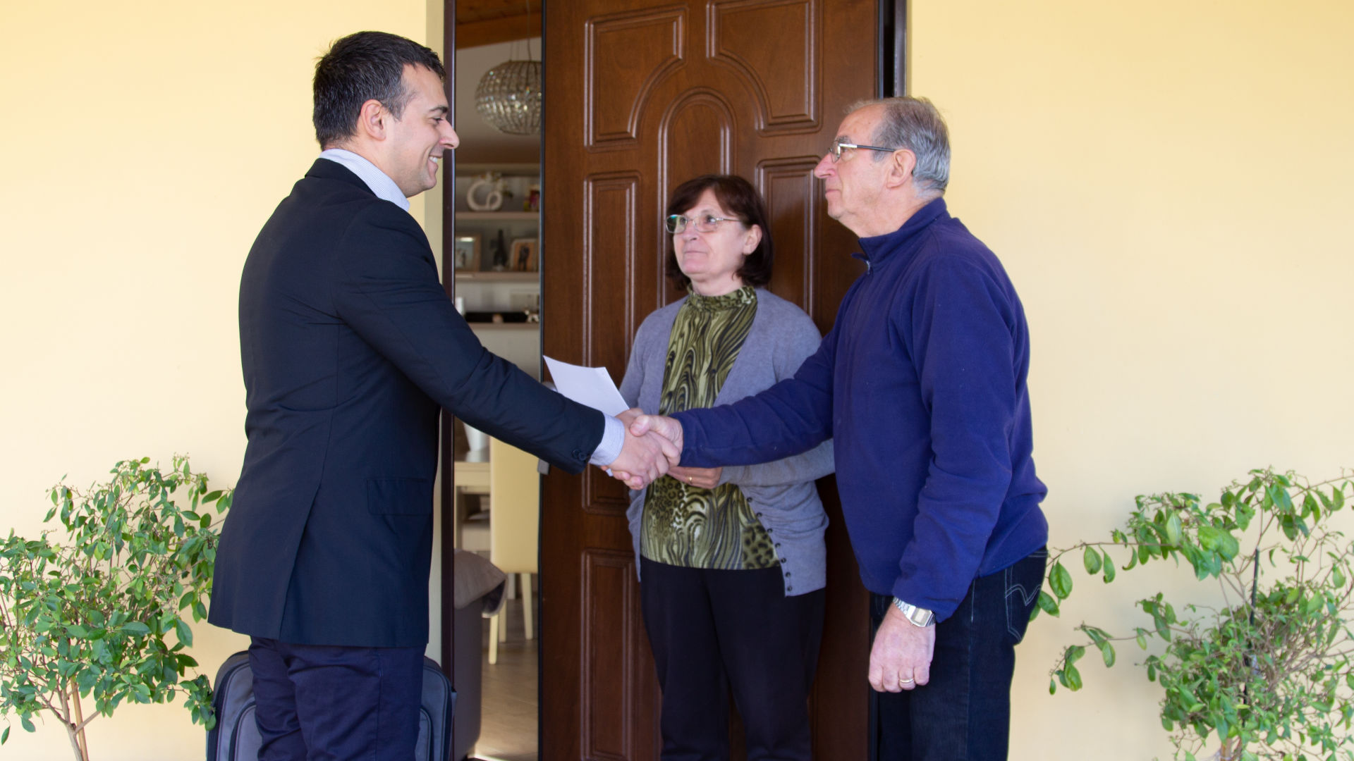 Un vendedor le da la mano a un hombre frente a la puerta.