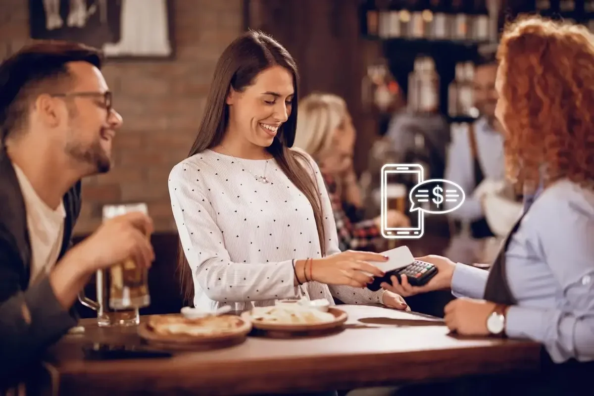 jovem-mulher-feliz-usando-smartphone-enquanto-paga-a-conta-garçonete-bar