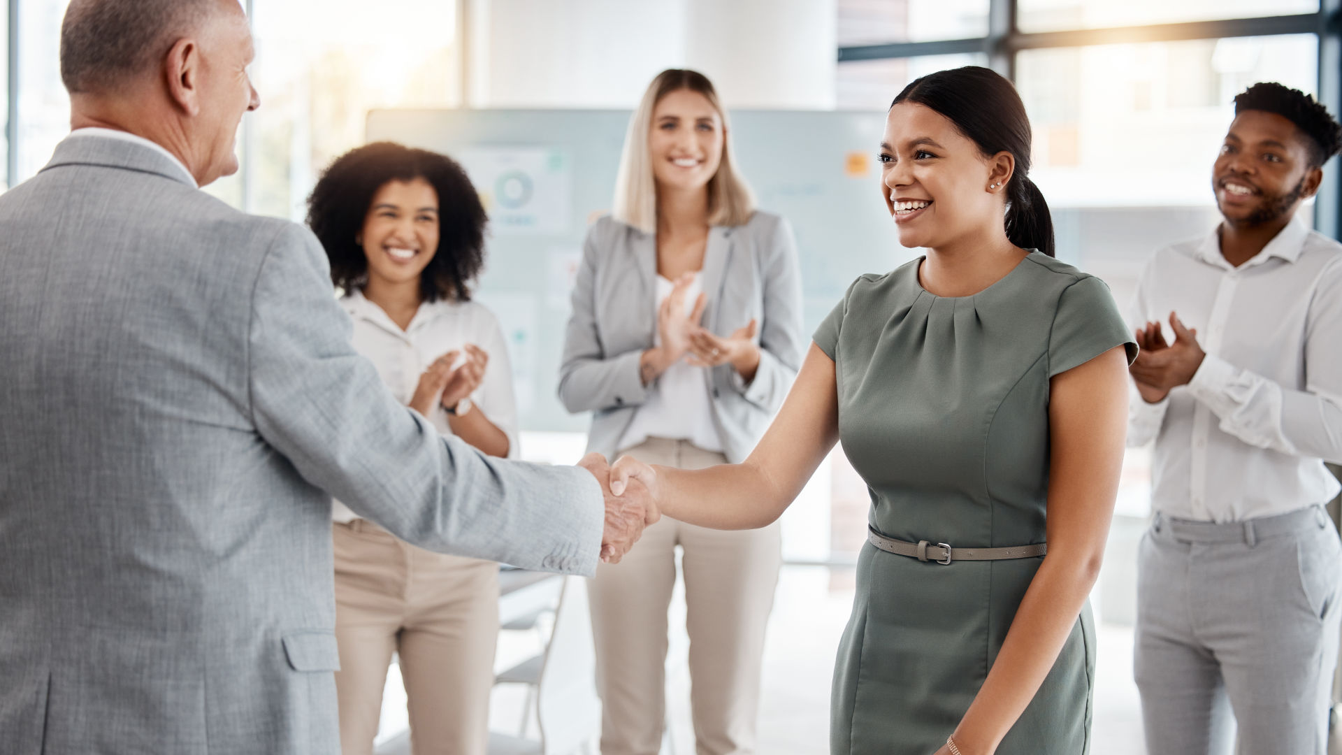 Um homem está apertando a mão de uma senhora dentro de um grupo de pessoas.