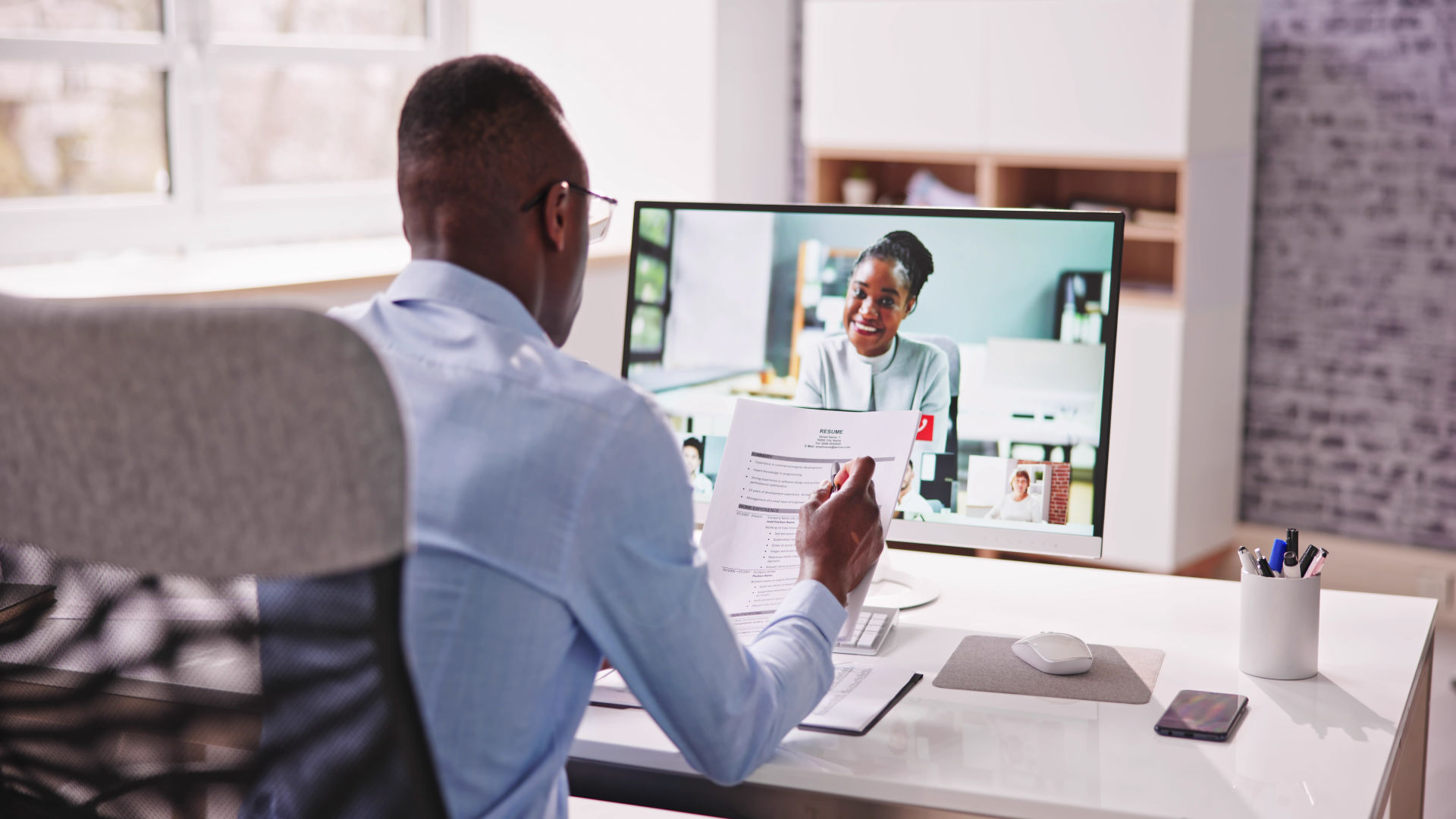 Um homem está entrevistando uma senhora por meio de uma reunião virtual.