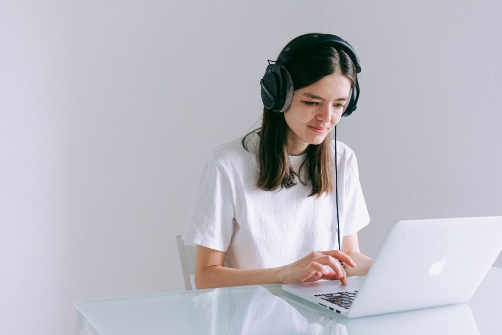 Wanita dengan headphone menggunakan laptop