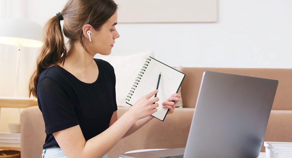 Mujer enfocada que usa una computadora portátil mientras asiste a un seminario web en línea