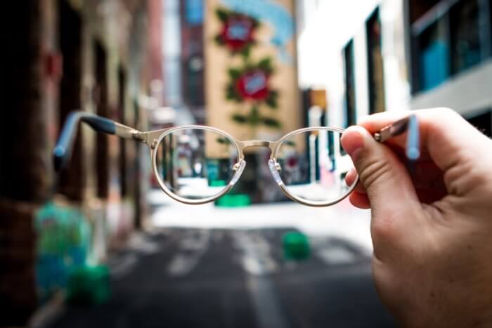 Gafas en primer plano con edificios altos en el fondo