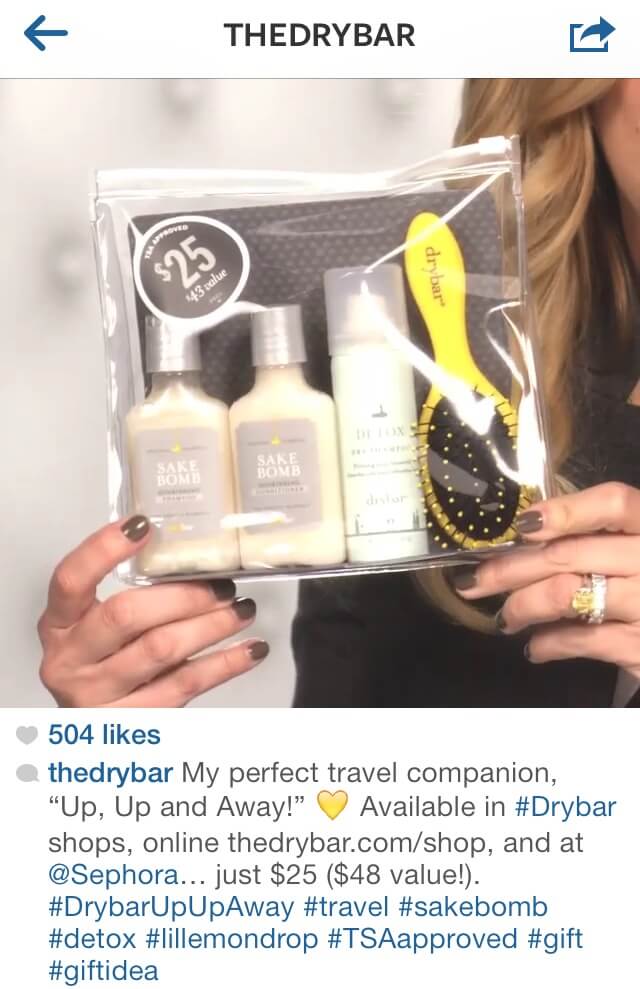 Postagem no Instagram da Drybar mais legenda e hashtag com um conjunto de produtos de cabelo para viagem.